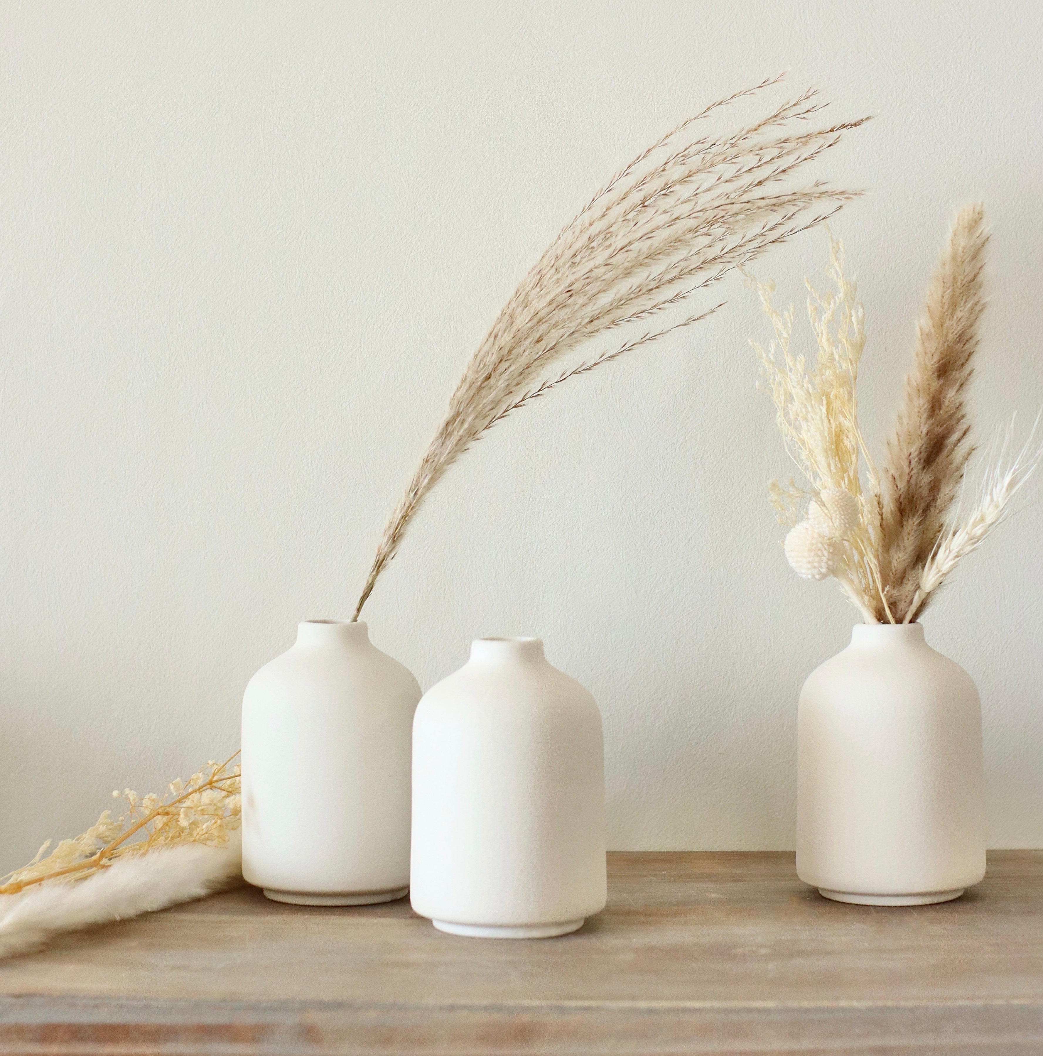 Individual white ceramic bud vase with dried flower
