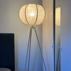 Tripod lamp with linen shade next to armchair