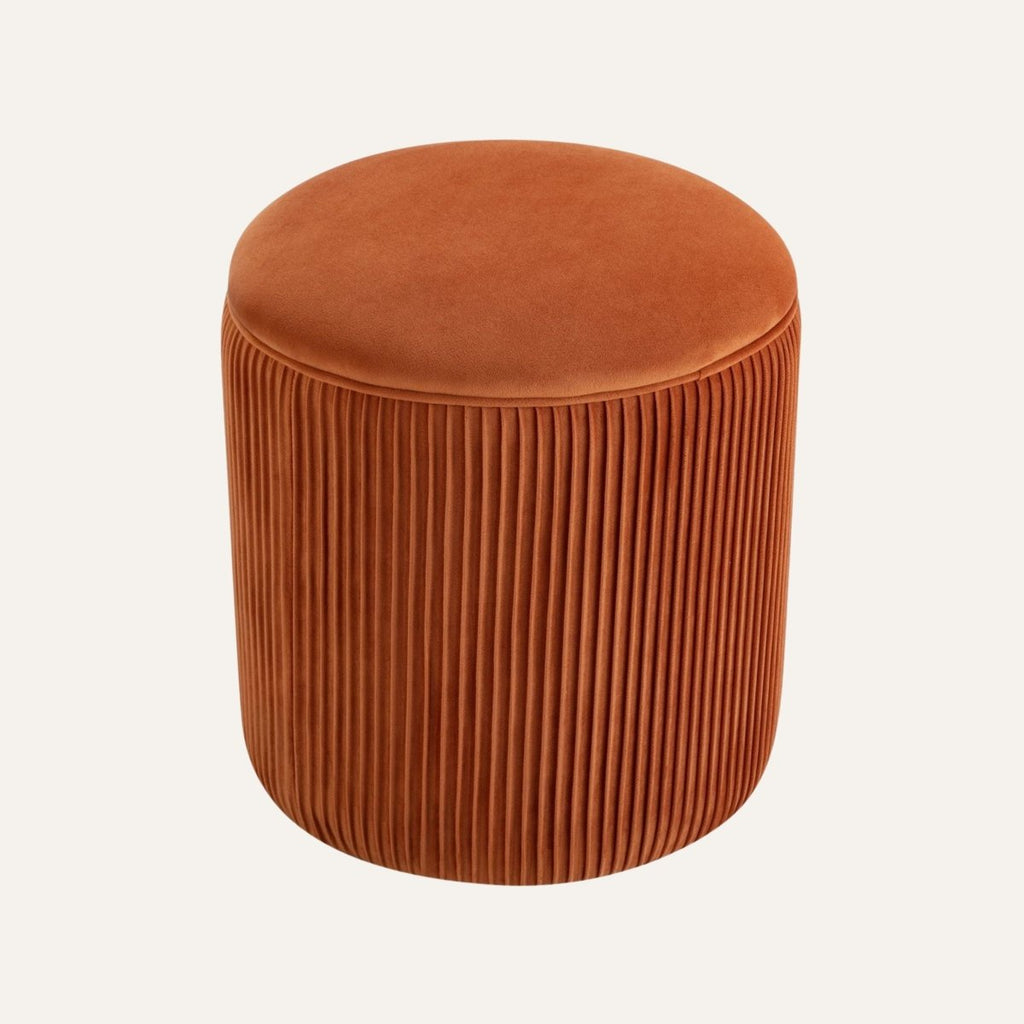 Round velvet ottoman in a modern living room setting